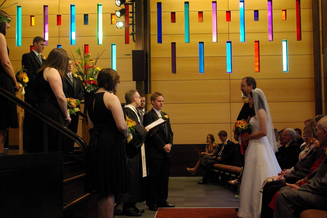 Exchanging vows beside the sanctuary's maple wall set with vertical panes of coloured glass