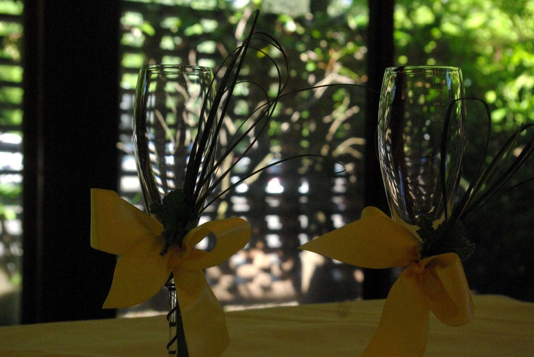 Two ribboned champagne flutes against a lattice screen and green courtyard light