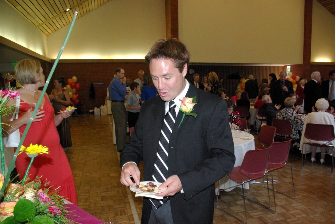 The groom mid-sentence at the buffet table as the reception fills up