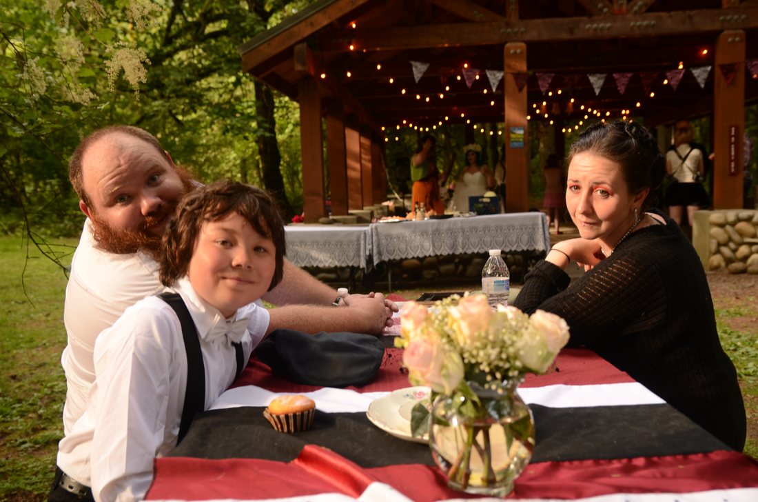 Guests at a reception picnic table with the string-lit shelter behind them