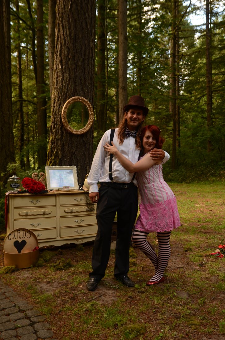 Two guests posing by a mirror hung on a Douglas fir beside the card table