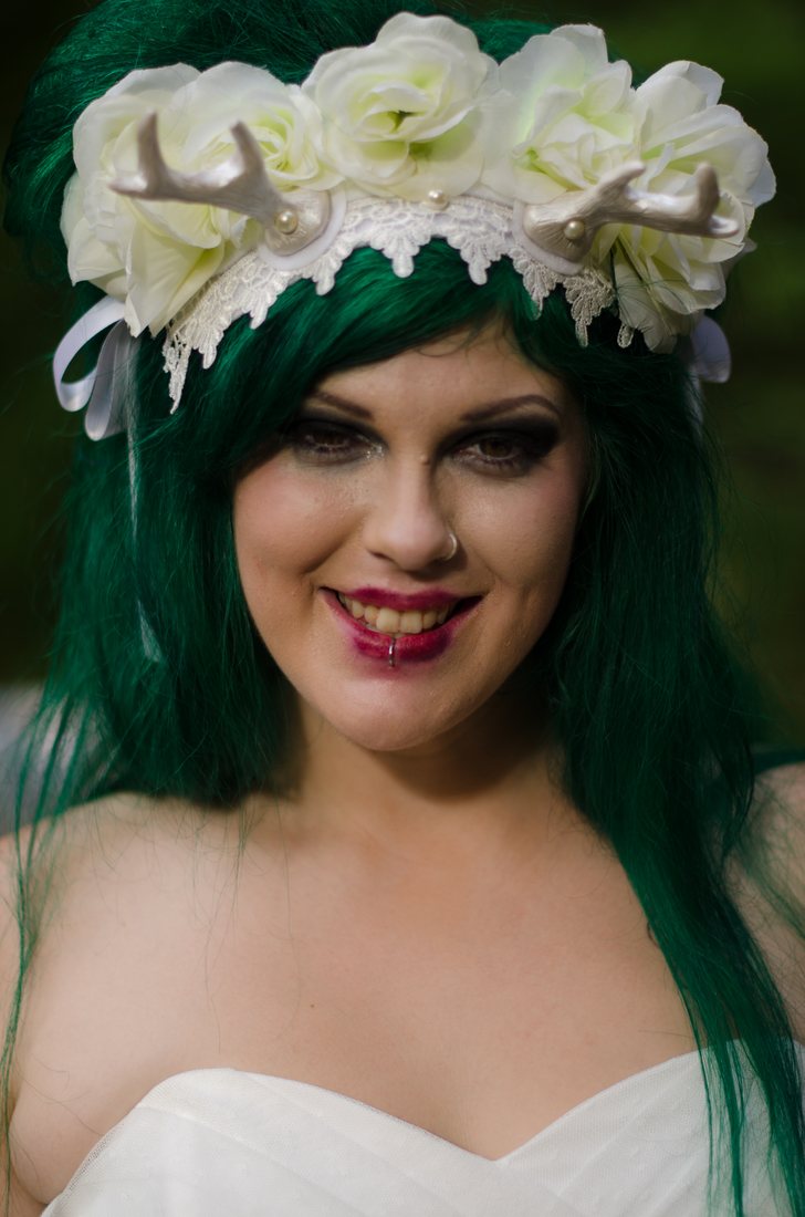 Portrait of the bride in a white rose and antler crown, green hair loose